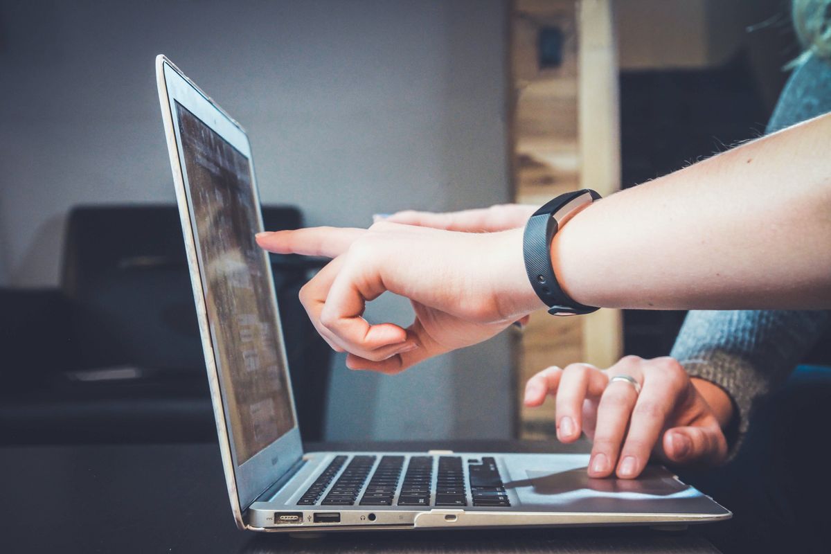 Iemand buiten beeld wijst iets aan op het scherm van een laptop